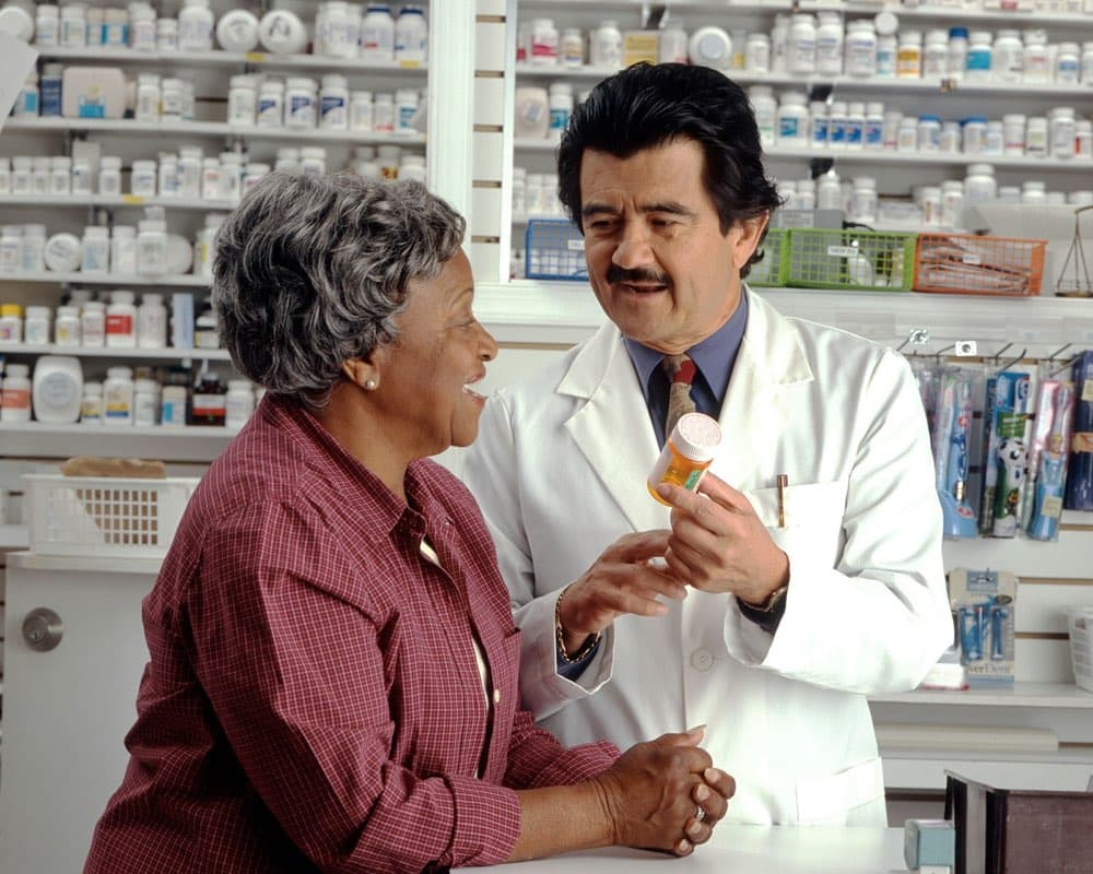 A pharmacist showing a customer a medicine at the shelves